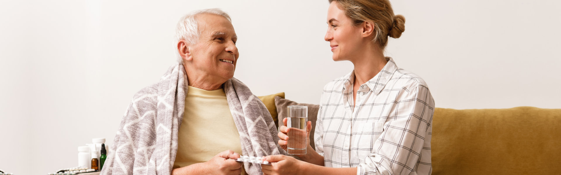 woman assisting a senior man on taking his medicine